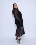 Load image into Gallery viewer, Plus Size Aphrodite Black Holiday Resort Dress with hoodie and black undergarment shown from the side, paired with gold and black sneakers.