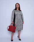 Load image into Gallery viewer, Women's Plus Size Black White Animal Print Bodycon Midi Vegan Leather Dress styled with a red Michael Kors handbag and black heels for an elegant look.