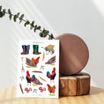 Load image into Gallery viewer, Biodegradable A5 sticker sheet with chicken and countryside illustrations.
